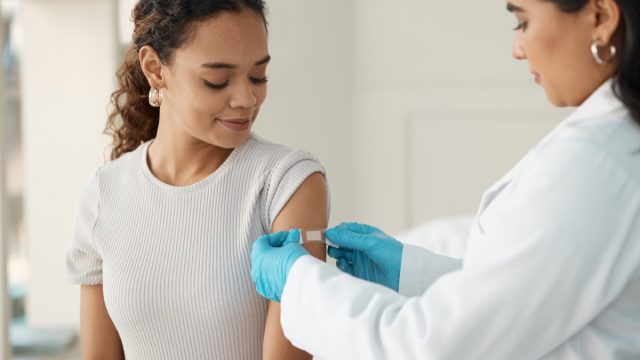 Shot of a young doctor applying a band-aid after injecting her patient during a consultation in the clinic