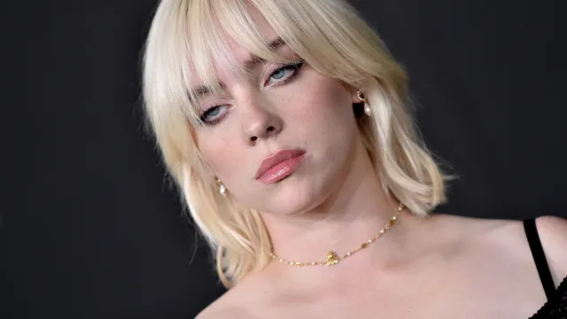 Billie Eilish with blonde hair and a wolf cut wearing a black top