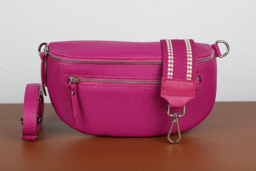 Bright pink belt bag sitting on a wood surface