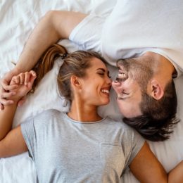 man and woman embracing in bed after waking up