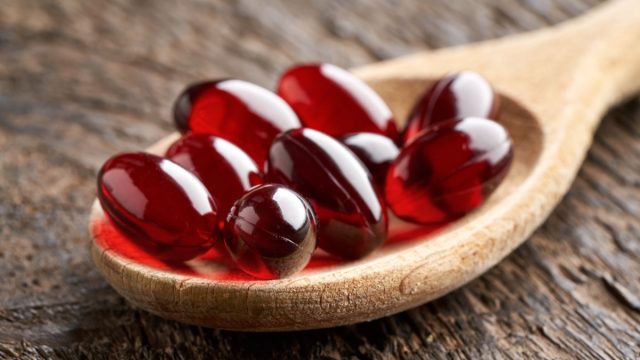 Red gel capsule supplements on a spoon beetroot