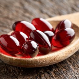 Red gel capsule supplements on a spoon beetroot