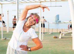 Old woman doing fitness exercises outdoors