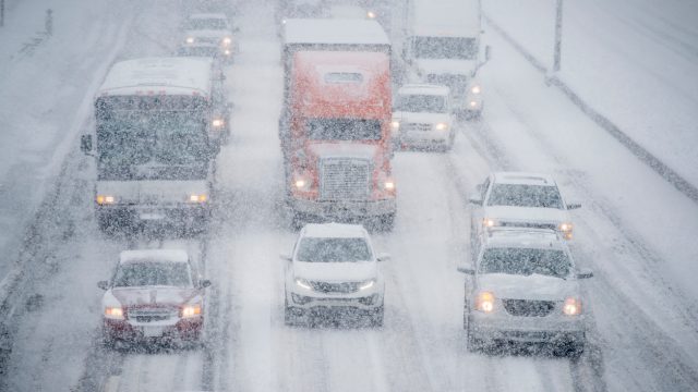 Trucks and cars driving down a highway in a snow storm