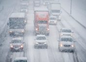 Trucks and cars driving down a highway in a snow storm