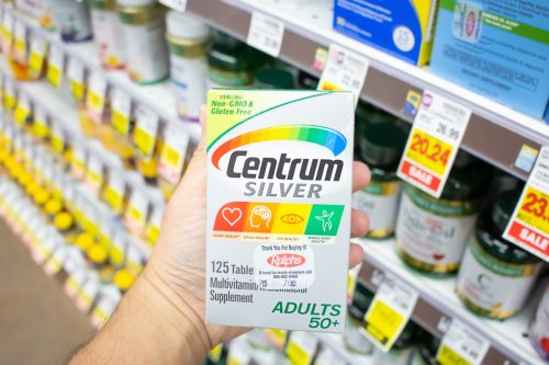 Los Angeles, California, United States - 08-10-2021: A view of a hand holding a package of Centrum Silver supplements, on display at a local grocery store.
