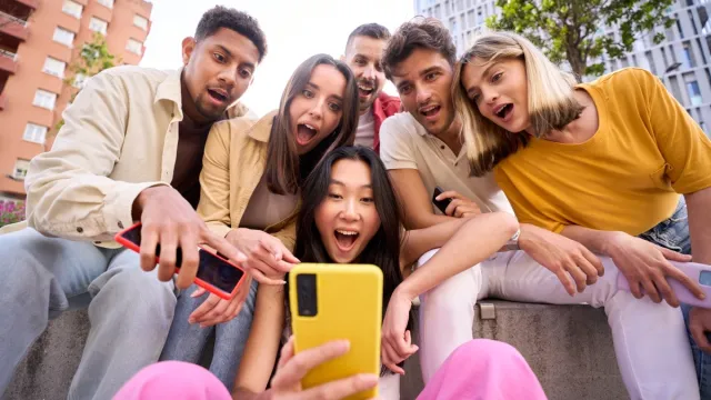 group of young people reading dirty jokes off their phones