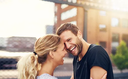 man and woman laughing and canoodling on the street