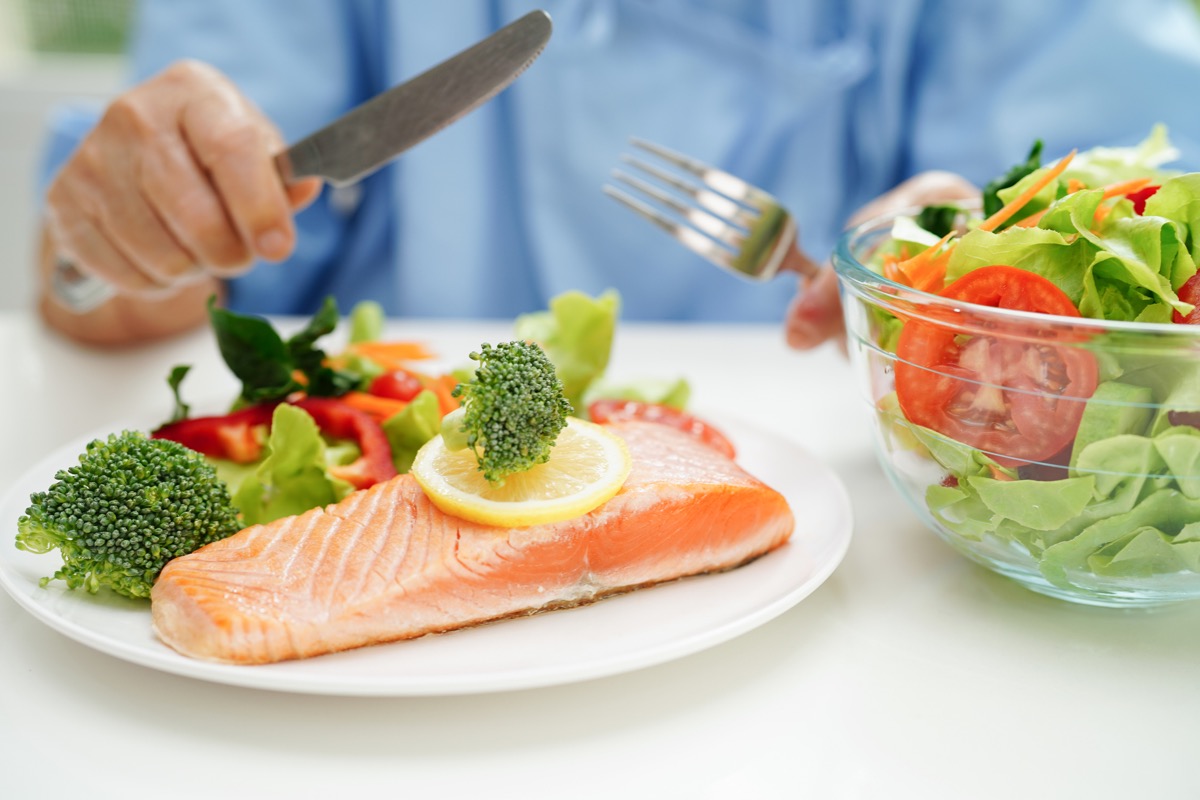 woman patient eating salmon stake and vegetable salad for healthy food in hospital