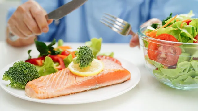woman patient eating salmon stake and vegetable salad for healthy food in hospital