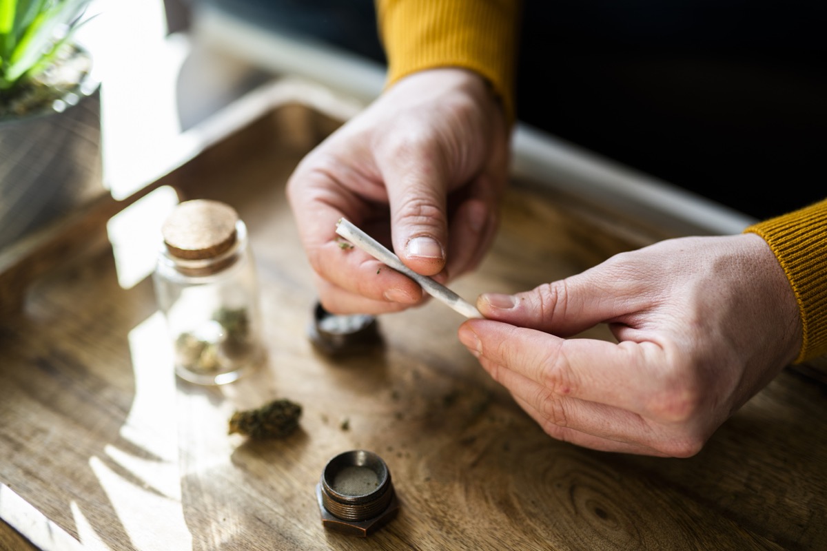 Close-up of a unrecognizable man's hands preparing a joint of marijuana.