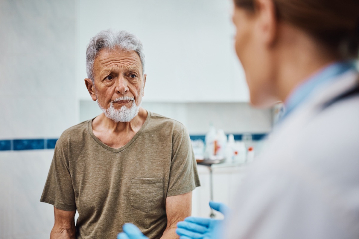 Concerned senior patient listening to his doctor after medical exam at the clinic.