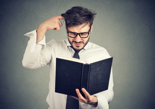 man looking through a book in search of cool words