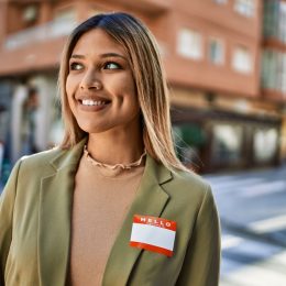 Young woman smiling on the street while wearing her name badge