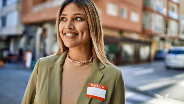Young woman smiling on the street while wearing her name badge