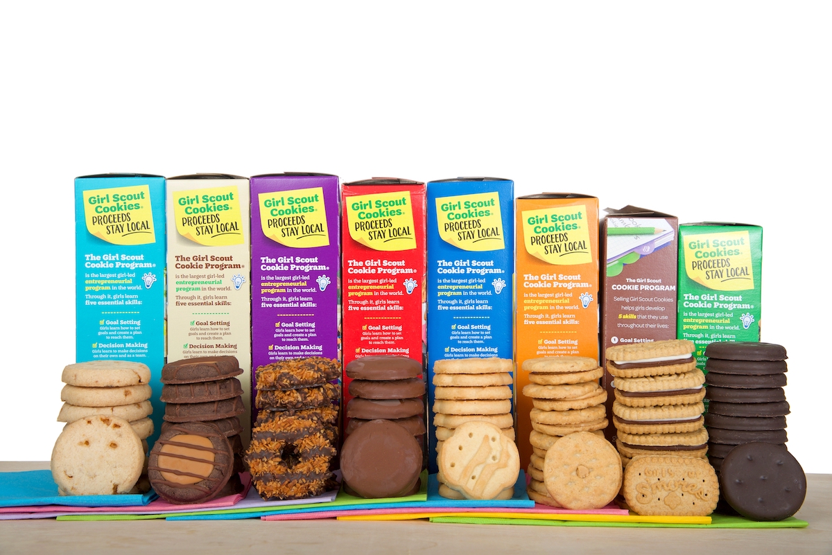 Girl Scout cookies in a row stacked in front of their colorful boxes