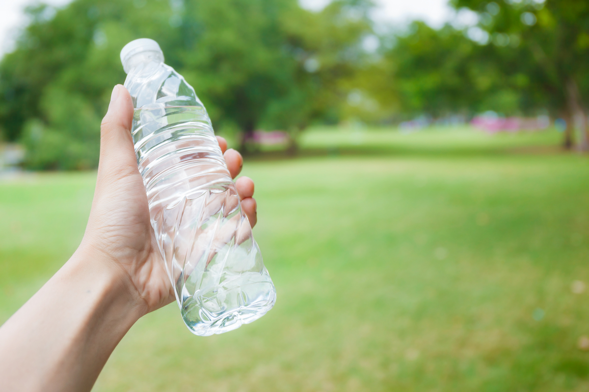 Hand holding fresh water bottle in the park