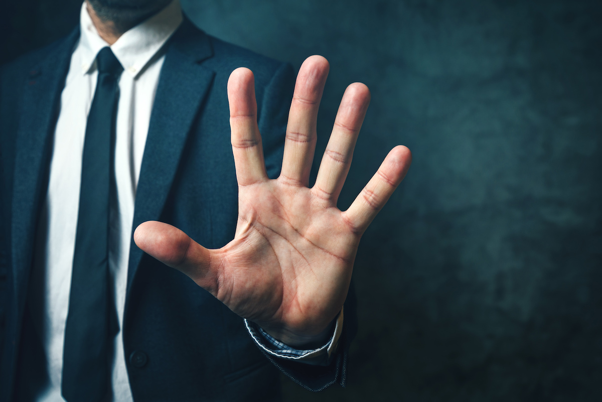 Cropped photo of a man in a navy blue suit holding out the palm of his hand