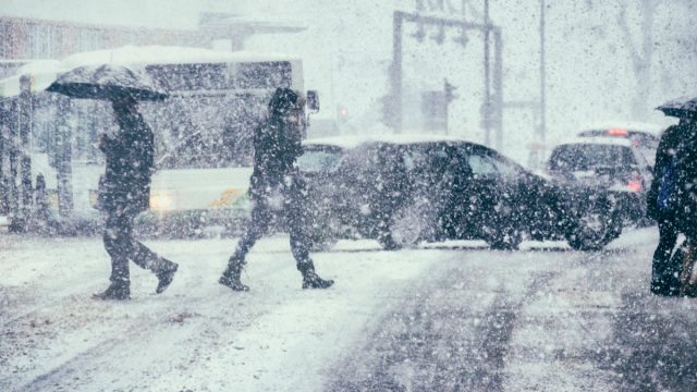 Pedestrians crossing a street during a snow storm