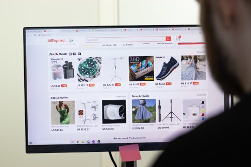 AliExpress website page on screen, with blurred out man using computer