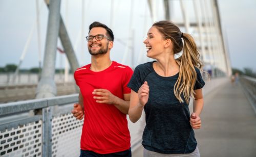 man and woman jogging together across a bridge