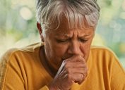 A senior woman coughing into her hand