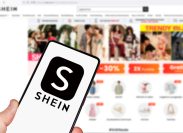 Shein logo on a smartphone in front of the website on a computer screen