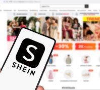 Shein logo on a smartphone in front of the website on a computer screen