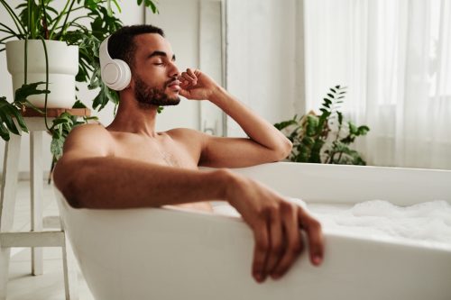 Young man relaxing in bath with headphones on