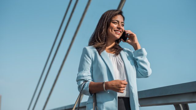 Beautiful business woman uses and talks on the phone abroad.