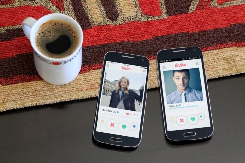 two cell phones on the table, each with a tinder profile on the screen