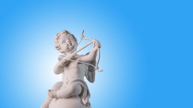 Figurine of an angel Cupid on the podium with a bow and arrow on a blu background