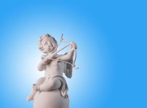 Figurine of an angel Cupid on the podium with a bow and arrow on a blu background