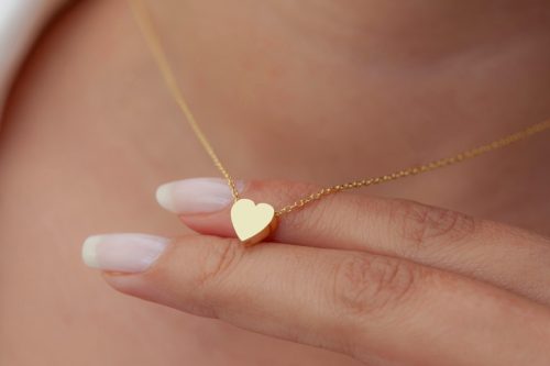 woman wearing a gold necklace in the shape of a heart