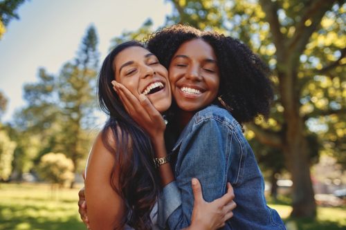 two women hugging each other in the park