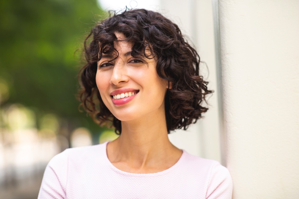 Portrait of smiling attractive young woman with short curly hair outdoors
