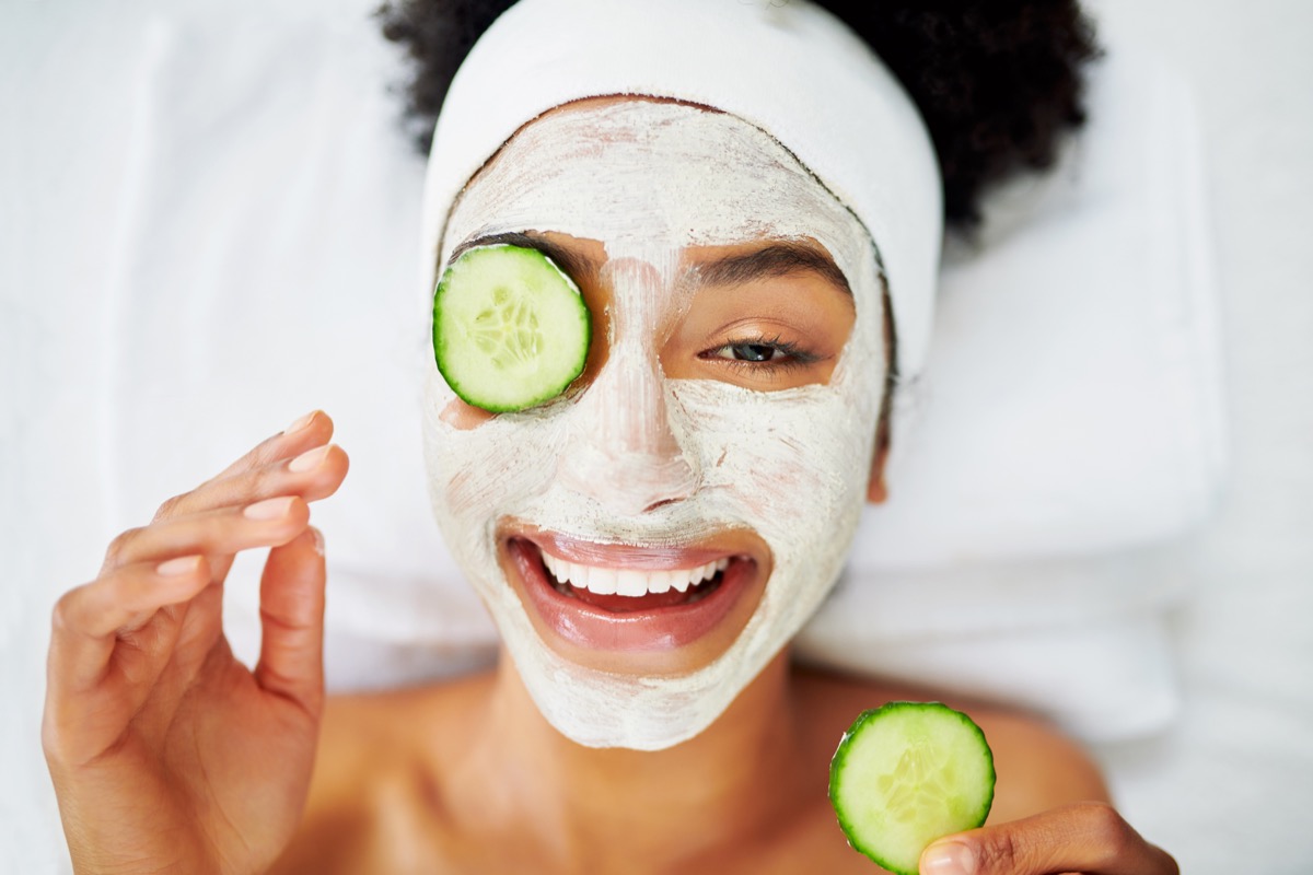 top-down closeup of a woman in a spa with a face mask and cucumbers on her eyes