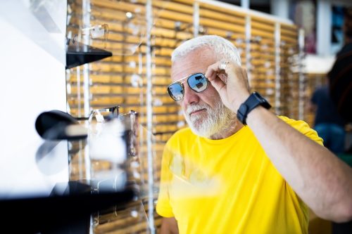 A senior man chooses glasses in an optical shop.