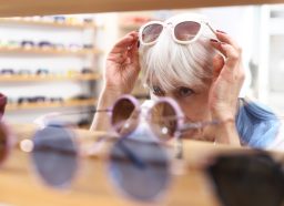 An older woman is trying on sunglasses in an optical store