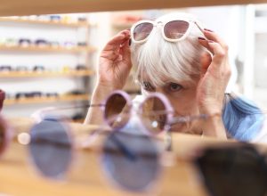 An older woman is trying on sunglasses in an optical store