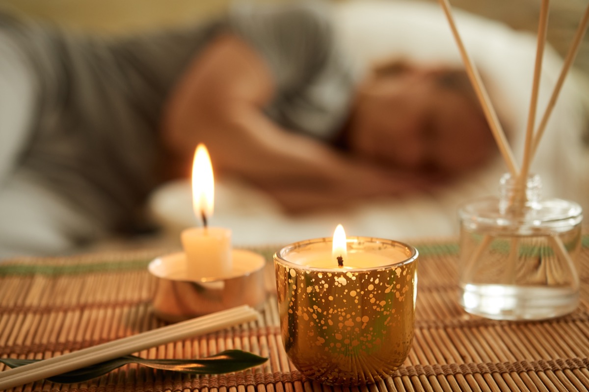Close-up of scented candle, diffuser, sleeping woman in the background. The concept of relaxation, mental health