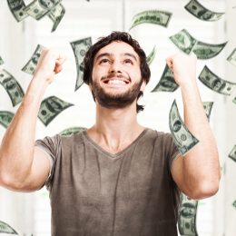 Portrait of a young man throwing money into the air against a white background
