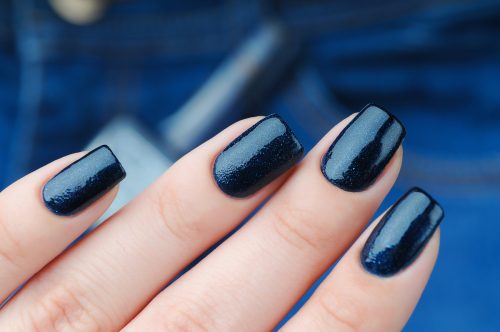 Close up of a hand with a dark blue manicure