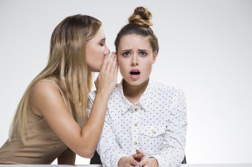 woman whispering scandalous, funny one-liners into her friend's ear