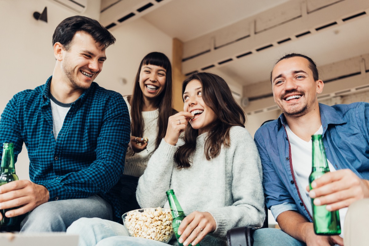 Two men and two women drinking beers and laughing while asking dirty would you rather questions