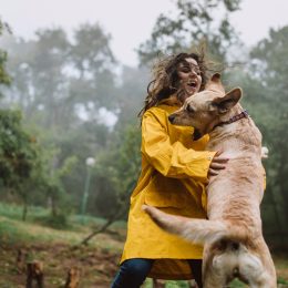 Young woman enjoying rainy day with her dog