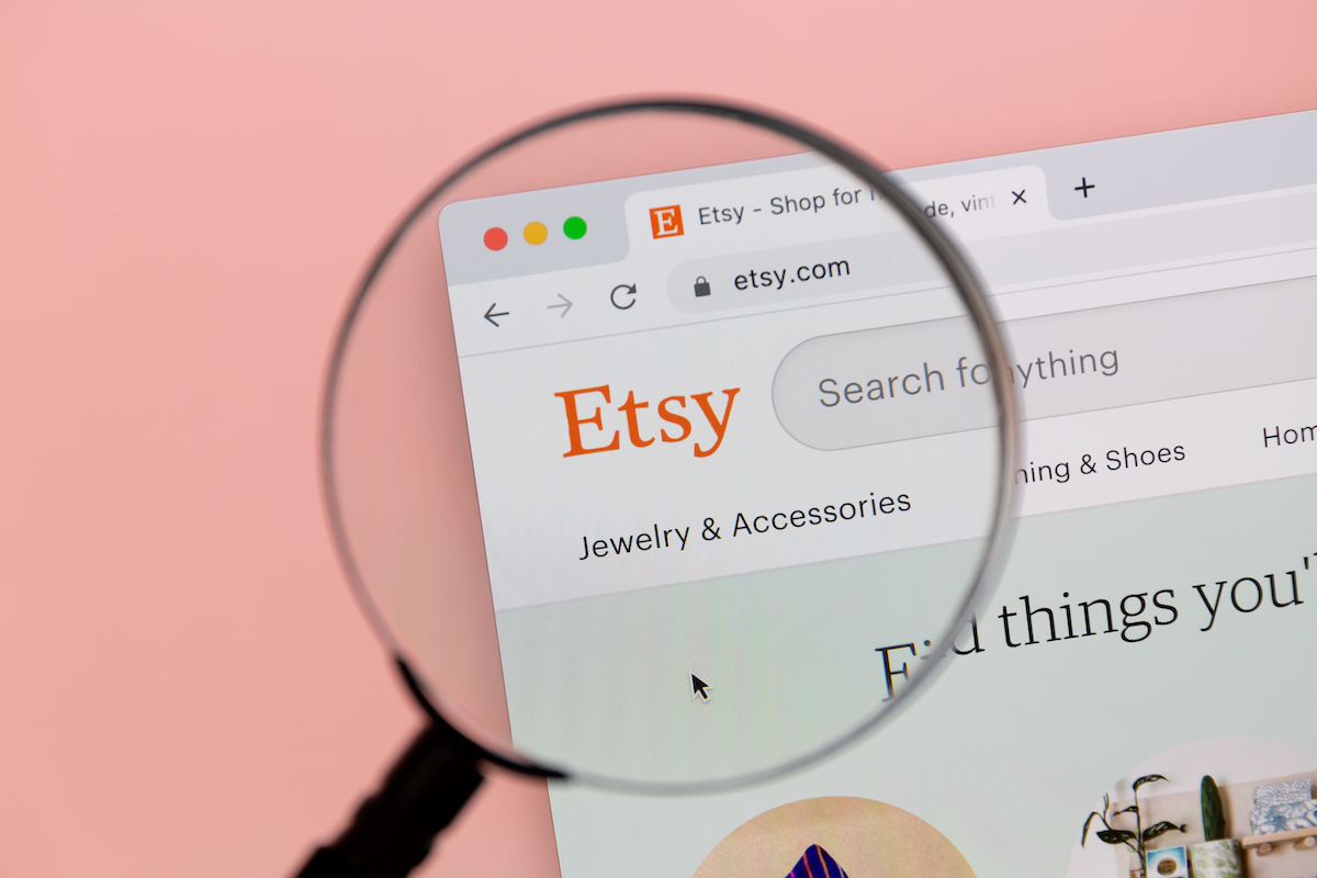 A magnifying lass over the Etsy logo on an internet page, against a light pink background