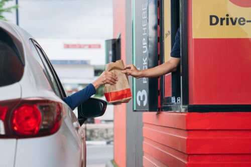 Young Man receiving food bag from fast food drive thru window