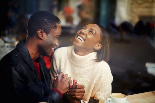 man and woman laughing together in a cafe