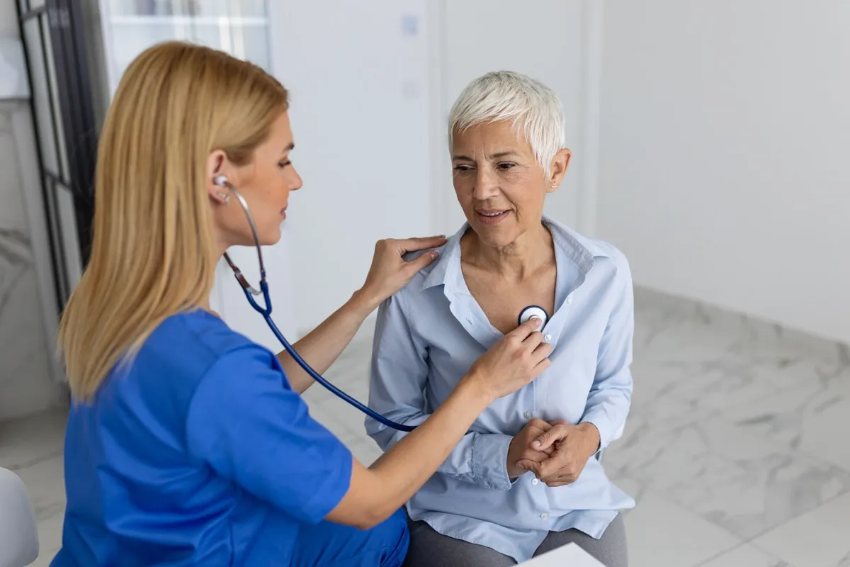 Woman nurse or GP use stethoscope listen to woman's heartbeat in clinic.